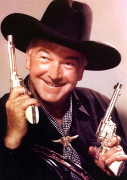 William Boyd as Hopalong Cassidy, guns raised.