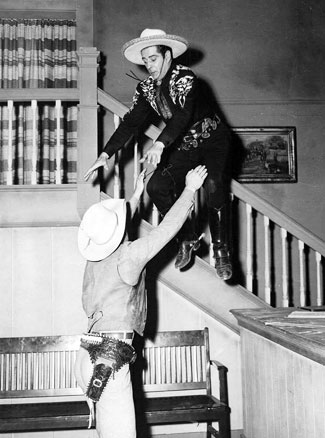 The camera catches Duncan Renaldo as the Cisco Kid mid-air-stunt into the arms of a waiting stuntman/heavy. 