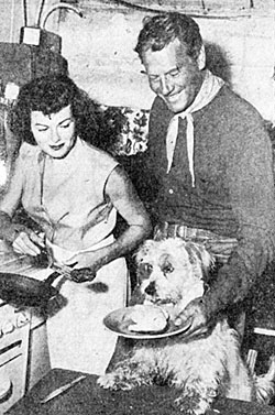 In between scenes for Universal’s “Lone Hand” (‘52) co-stars Barbara Hale and Joel McCrea cater to the hunger of dog actor Butch.