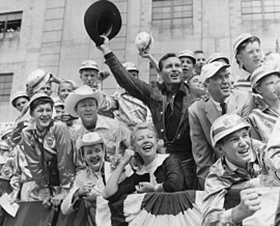 Soapbox Derby fans Roy Rogers, Dale Evans, Dinah Shore, George Montgomery and James Stewart sit in the stands with young racers and fans August 18, 1957 at Derby Downs in Akron, Ohio. 