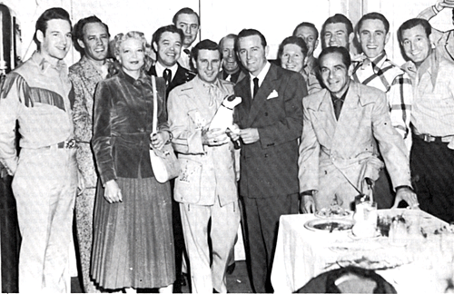 (L-R) Unidentified, possibly a member of Pee Wee King's band, Hank Penny, Cindy Walker, Wade Ray, Wesley Tuttle, Pee Wee King, Tim Spencer, Jimmy Wakley (holding a Capitol Records statuette), Redd Stewart, Lloyd Perriman, Tex Williams, Ken Curtis, Tommy Doss, Shug Fisher in foreground. Photo probably comemorates Jimmy's many hit records with Capitol. 