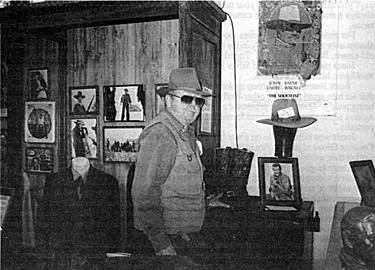 Costumer Luster Bayless stands beside John Wayne's hat, coat and boots
from "The Shootist". 