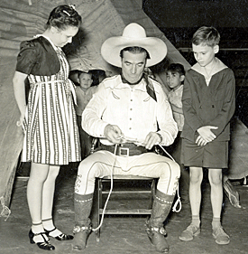 Tom Mix shows some young'uns how to tie a special kind of knot.