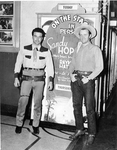 Anybody recognize these two gentlemen posed before the in-person placard for Raymond Hatton? Not sure where the theater was but the photographer was Charles Pugh of Erwin, Tennessee, in 1946. (Note the lobby cards for “Desert Horseman” with Charles Starrett on the left. (Thanx to John Bickler.)