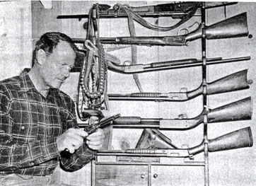 Joel McCrea looks over his ranchhouse gun rack.