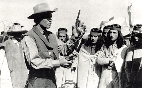 Kelo Henderson, star of TV's "26 Men", displays his expertise in six-gun handling and fast draw before a group of attentive "Indians" in Germany while Kelo was filming "Pyramid of the Sun God" with Lex Barker in 1965.